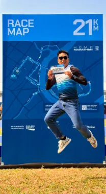 Thuận cầm bib và nhảy trước bảng đường chạy HCMC Marathon