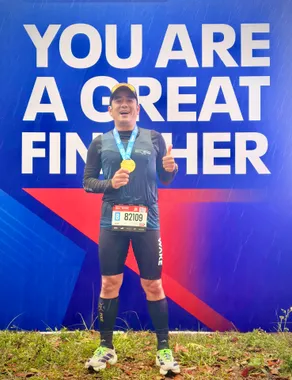 Thuận cầm huy chương trước bảng finisher