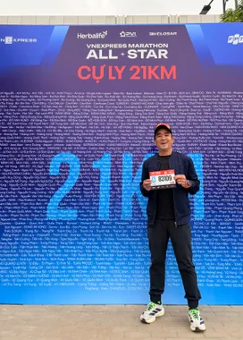 Thuận cầm bib trước bảng tên VnExpress Marathon All-Star